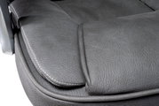 Nahaufnahme der Sitzfläche eines Chefsessels aus grauem Leder mit sichtbaren Nähten, seitliche Perspektive.
