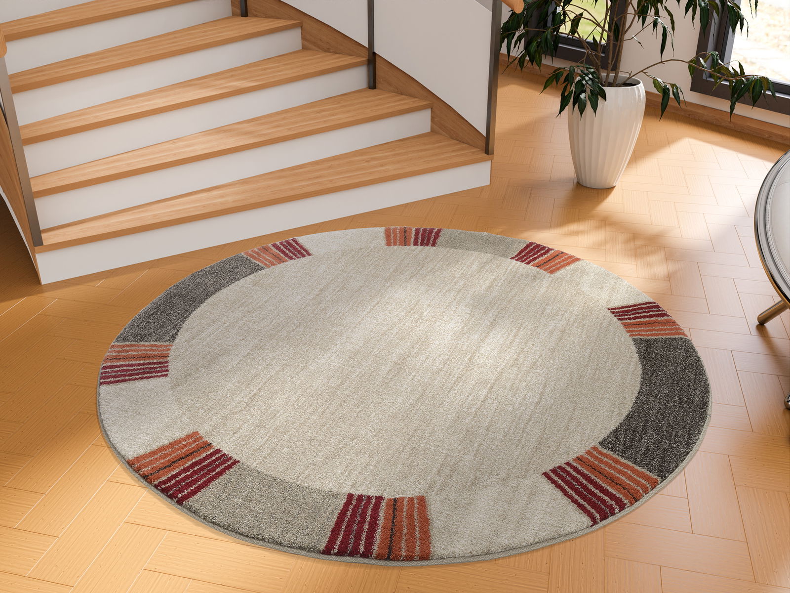 Runder Frisé-Teppich mit grauen, roten und orangefarbenen Akzenten auf hellem Hintergrund, in einem modernen Raum neben einer Treppe, aus der Vogelperspektive betrachtet.