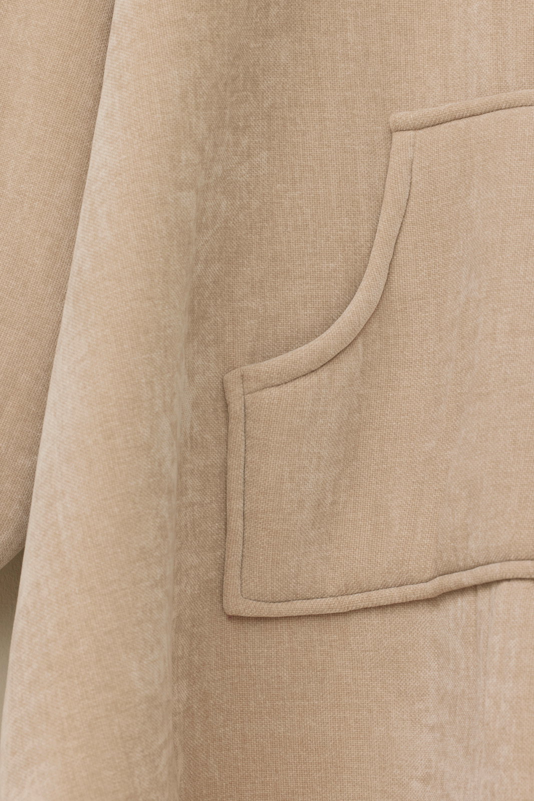 Nahaufnahme eines beigen Lounge Hoodies mit einer Tasche, seitliche Perspektive