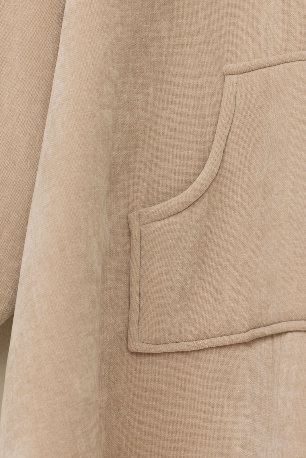 Nahaufnahme eines beigen Lounge Hoodies mit einer Tasche, seitliche Perspektive