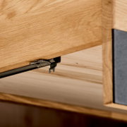 Detailfoto van een scharnier aan een houten dressoir, gezien vanuit een laag standpunt.
